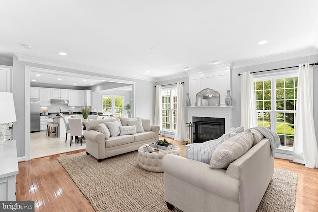41311 Silverside Dr, Leesburg, VA 20175 - living room with plenty of natural light, a glass covered fireplace, light wood-style flooring, ornamental molding, and recessed lighting