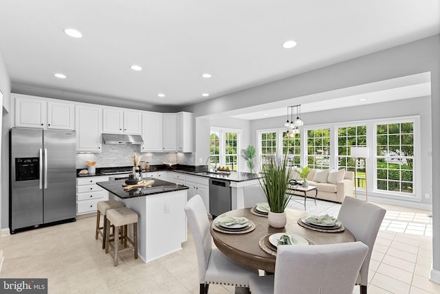 41311 Silverside Dr, Leesburg, VA 20175 - kitchen with stainless steel appliances, under cabinet range hood, dark countertops, a center island, and white cabinets
