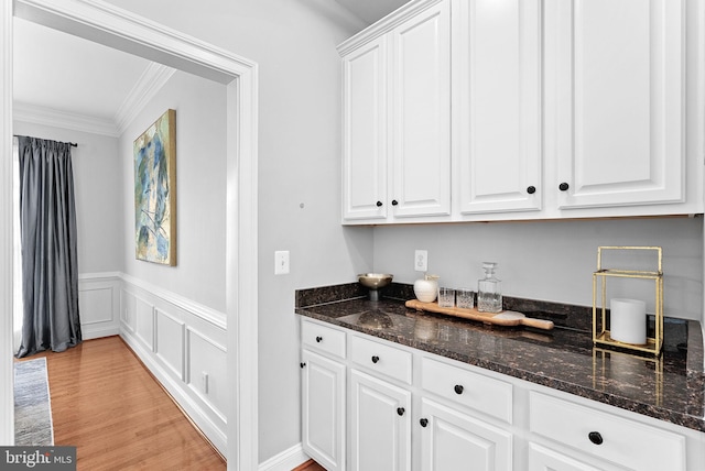 41311 Silverside Dr, Leesburg, VA 20175 - kitchen featuring crown molding, white cabinets, wainscoting, dark stone countertops, and light wood finished floors