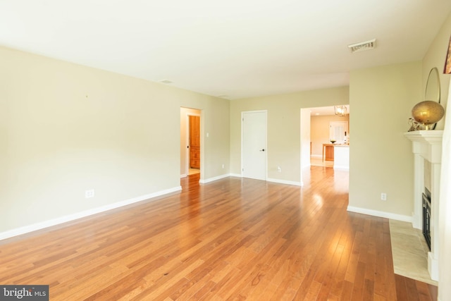 724 E Curtin St, Bellefonte, PA 16823 - unfurnished living room featuring a fireplace with flush hearth, light wood-type flooring, and baseboards