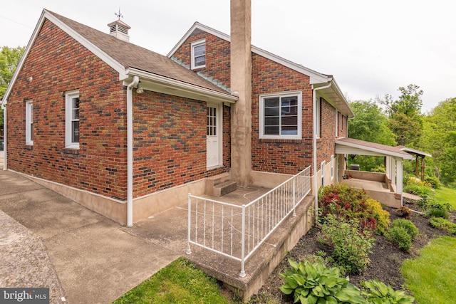 724 E Curtin St, Bellefonte, PA 16823 - view of property exterior with a chimney, brick siding, and roof with shingles