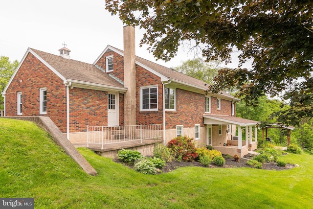 724 E Curtin St, Bellefonte, PA 16823 - rear view of house with a porch, a chimney, a lawn, and brick siding
