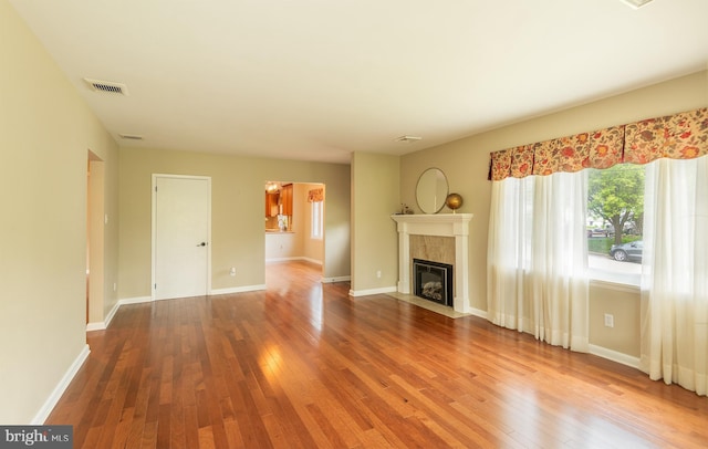 724 E Curtin St, Bellefonte, PA 16823 - unfurnished living room with hardwood / wood-style floors, a tiled fireplace, and baseboards