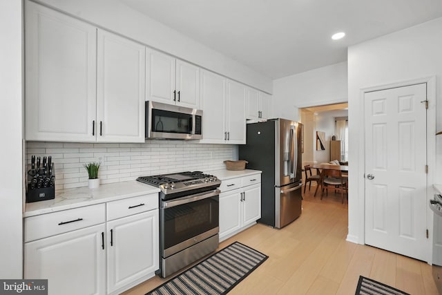 47686 Sandbank Sq, Sterling, VA 20165 - kitchen featuring appliances with stainless steel finishes, white cabinetry, decorative backsplash, light wood-style flooring, and recessed lighting