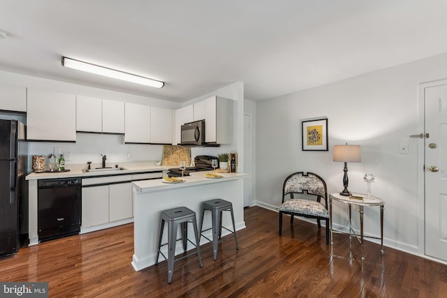 304 Duncan Ave Unit F, Alexandria, VA 22301 - kitchen featuring black appliances, light countertops, a peninsula, white cabinetry, and a breakfast bar area