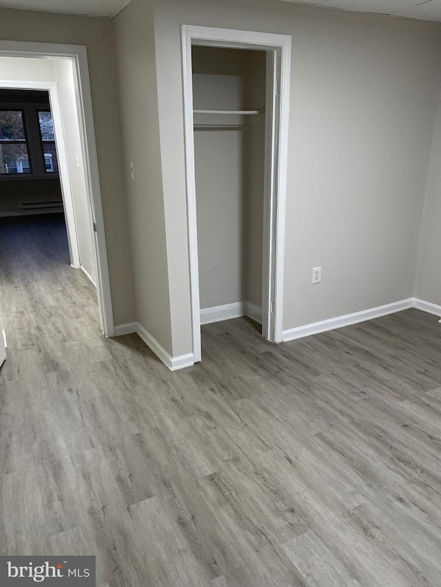 3816 Fairhaven Ave, Baltimore City, MD 21226 - unfurnished bedroom with wood finished floors, baseboards, a closet, and a baseboard heating unit