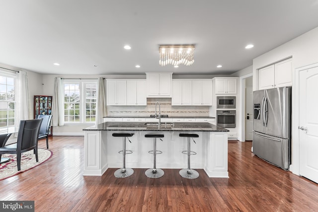 131 Pierce Ln, Kennett Square, PA 19348 - kitchen featuring appliances with stainless steel finishes, a sink, a breakfast bar area, backsplash, and white cabinets