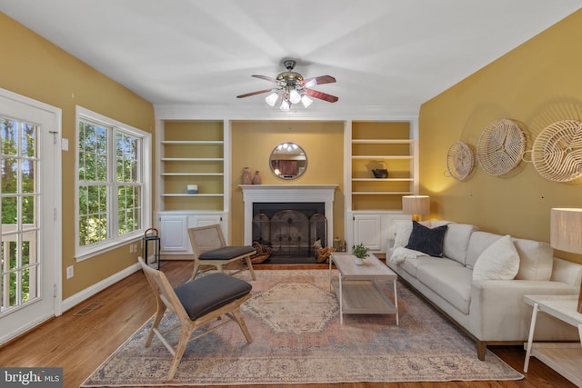 2121 Chaucer Way, Woodstock, MD 21163 - living area featuring built in features, a ceiling fan, a fireplace with flush hearth, baseboards, and wood finished floors
