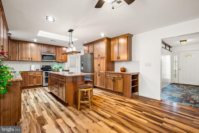 2460 Mill Rd, Quakertown, PA 18951 - kitchen with stainless steel appliances, brown cabinetry, a kitchen island, decorative backsplash, and a kitchen bar