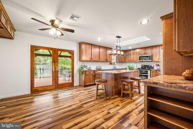 2460 Mill Rd, Quakertown, PA 18951 - kitchen with stainless steel appliances, brown cabinetry, light wood finished floors, a kitchen breakfast bar, and a center island