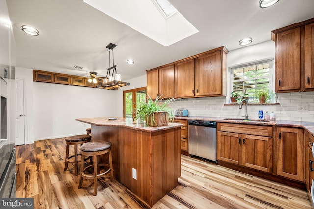 2460 Mill Rd, Quakertown, PA 18951 - kitchen featuring stainless steel dishwasher, a sink, a skylight, brown cabinetry, and light wood-style floors
