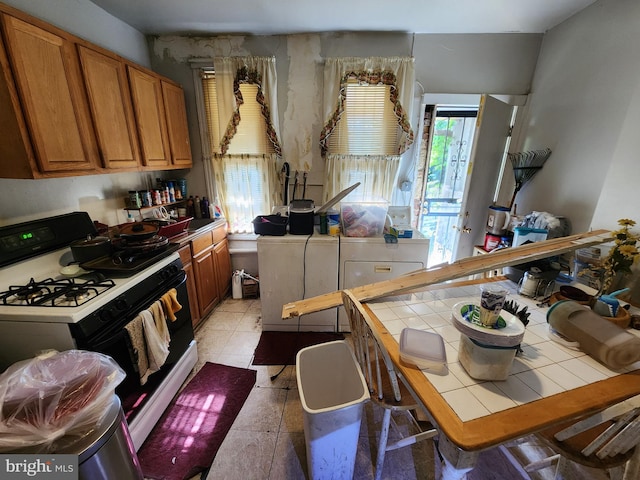 329 S Calhoun St, Baltimore, MD 21223 - kitchen with range with gas stovetop, tile counters, and brown cabinets
