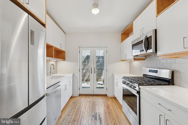 439 Mercy St, Philadelphia, PA 19148 - kitchen with appliances with stainless steel finishes, open shelves, a sink, french doors, and white cabinetry
