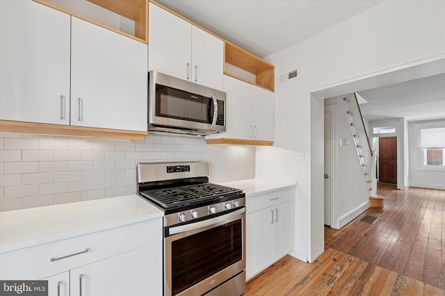 439 Mercy St, Philadelphia, PA 19148 - kitchen with appliances with stainless steel finishes, light wood finished floors, light countertops, backsplash, and white cabinetry