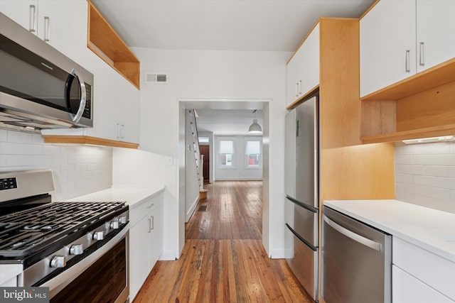 439 Mercy St, Philadelphia, PA 19148 - kitchen featuring stainless steel appliances, light countertops, white cabinets, light wood-style floors, and backsplash