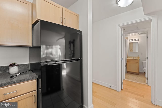 800 4th St SW Unit N216, Washington, DC 20024 - kitchen with freestanding refrigerator, light brown cabinetry, light wood-style floors, dark countertops, and a sink