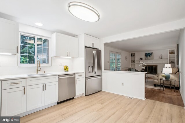 944 War Admiral St, Great Falls, VA 22066 - kitchen featuring appliances with stainless steel finishes, a sink, open floor plan, light wood-style flooring, and white cabinets