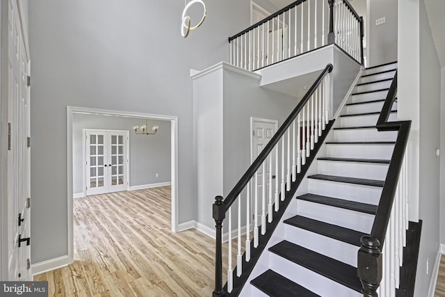 1201 Falls Grove Ln, York, PA 17404 - staircase featuring a towering ceiling, wood finished floors, a chandelier, baseboards, and french doors