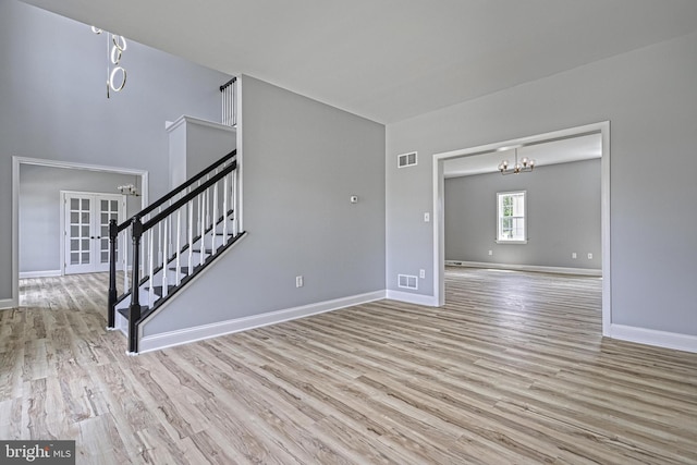 1201 Falls Grove Ln, York, PA 17404 - unfurnished living room with a chandelier, stairs, wood finished floors, baseboards, and french doors