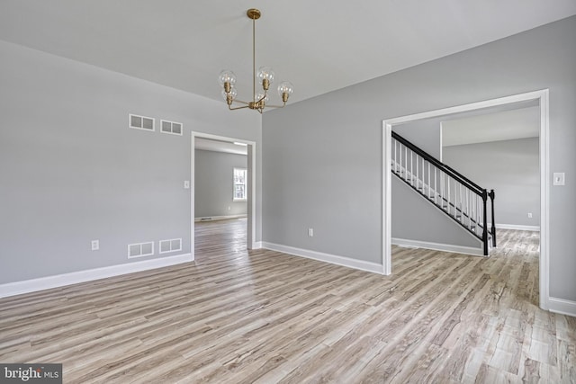 1201 Falls Grove Ln, York, PA 17404 - empty room featuring light wood finished floors, a chandelier, baseboards, and stairs