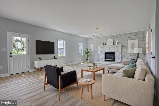1201 Falls Grove Ln, York, PA 17404 - living room featuring healthy amount of natural light, a chandelier, light wood finished floors, and a stone fireplace