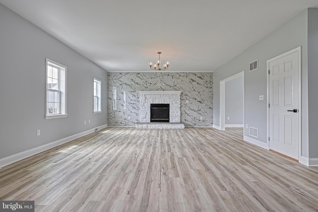 1201 Falls Grove Ln, York, PA 17404 - unfurnished living room with an accent wall, a chandelier, light wood-style flooring, and baseboards