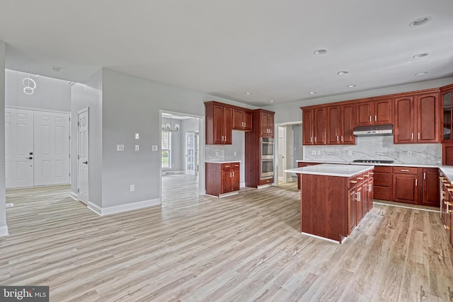 1201 Falls Grove Ln, York, PA 17404 - kitchen featuring under cabinet range hood, stainless steel double oven, light wood-style floors, tasteful backsplash, and recessed lighting