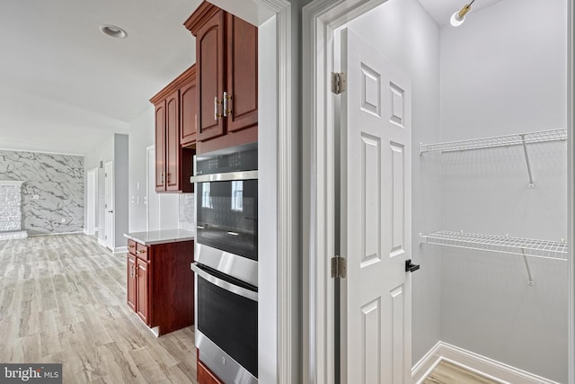 1201 Falls Grove Ln, York, PA 17404 - kitchen featuring stainless steel double oven, reddish brown cabinets, light wood-style floors, and baseboards