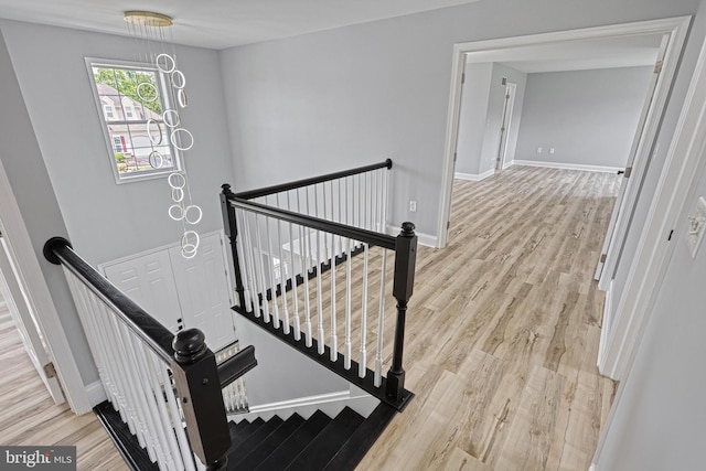 1201 Falls Grove Ln, York, PA 17404 - stairway featuring wood finished floors, a chandelier, and baseboards
