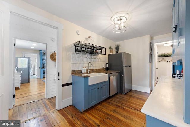 123 Coral St, Beach Haven, NJ 08008 - kitchen with blue cabinets, appliances with stainless steel finishes, a sink, hardwood / wood-style flooring, and tasteful backsplash