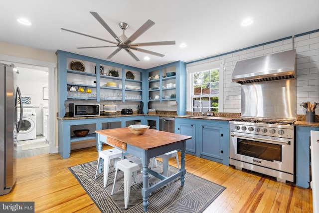 123 Coral St, Beach Haven, NJ 08008 - kitchen with stainless steel appliances, washer / dryer, wall chimney range hood, blue cabinets, and a ceiling fan