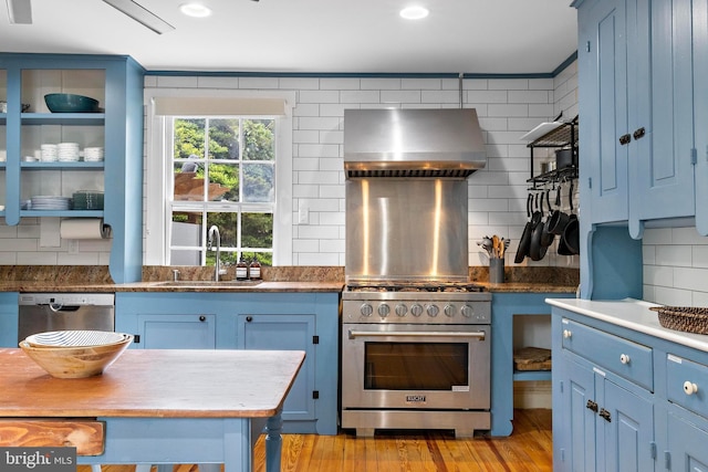 123 Coral St, Beach Haven, NJ 08008 - kitchen with stainless steel appliances, wall chimney exhaust hood, a sink, blue cabinets, and backsplash