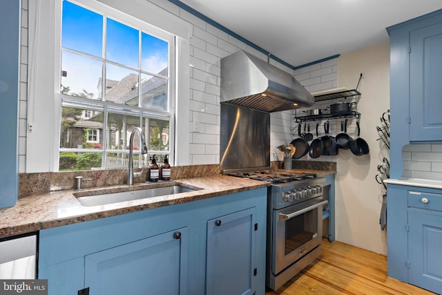 123 Coral St, Beach Haven, NJ 08008 - kitchen with stainless steel range, wall chimney range hood, a sink, blue cabinets, and backsplash