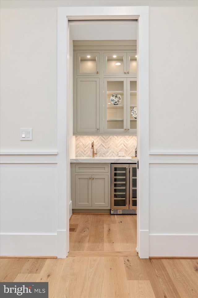 6613 Byrnes Dr, Mclean, VA 22101 - indoor wet bar featuring beverage cooler, light wood-style floors, backsplash, and baseboards