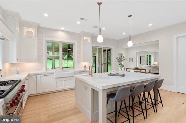 6613 Byrnes Dr, Mclean, VA 22101 - kitchen with a sink, a kitchen island with sink, custom range hood, white cabinets, and double oven range