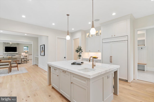 6613 Byrnes Dr, Mclean, VA 22101 - kitchen with a sink, light wood-type flooring, paneled refrigerator, an island with sink, and light stone countertops