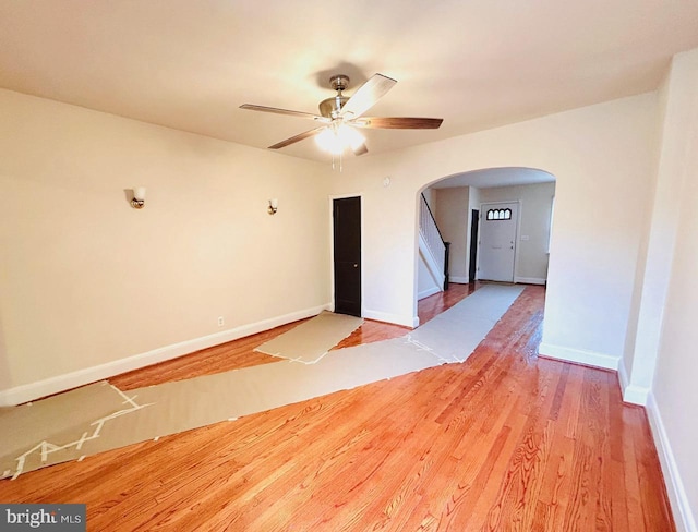 3925 Colborne Rd, Baltimore, MD 21229 - spare room with arched walkways, a ceiling fan, wood finished floors, baseboards, and stairs