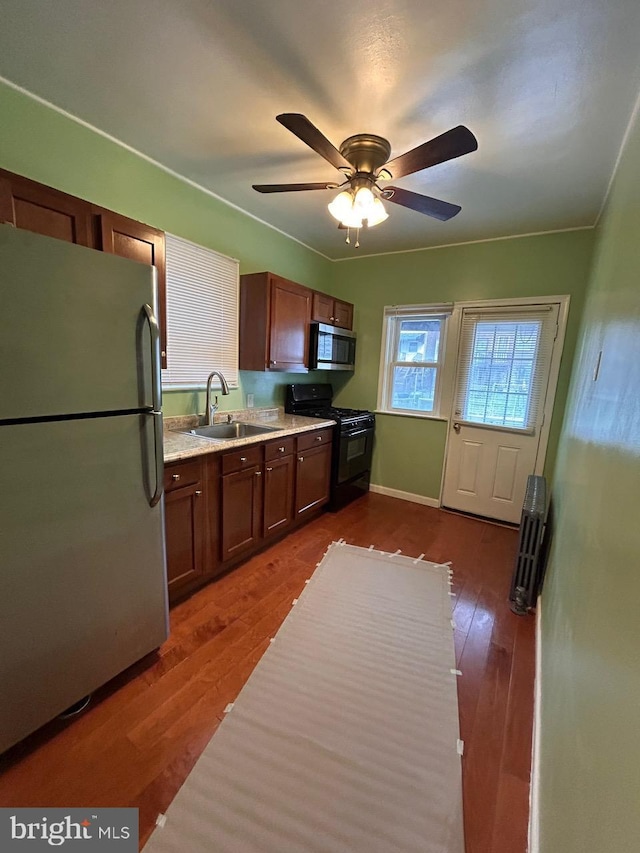 3925 Colborne Rd, Baltimore, MD 21229 - kitchen featuring appliances with stainless steel finishes, a sink, dark wood-style floors, a ceiling fan, and light stone countertops
