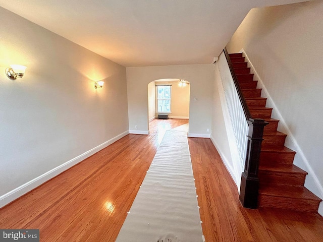 3925 Colborne Rd, Baltimore, MD 21229 - hallway featuring arched walkways, wood finished floors, stairs, and baseboards