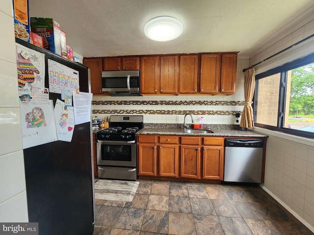 74 Probasco Rd, Hightstown, NJ 08520 - kitchen featuring appliances with stainless steel finishes, brown cabinetry, a sink, dark stone finish floors, and a textured ceiling