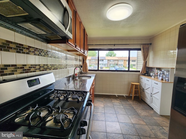 74 Probasco Rd, Hightstown, NJ 08520 - kitchen featuring stainless steel gas stove, a sink, tile walls, a textured ceiling, and stone tile flooring