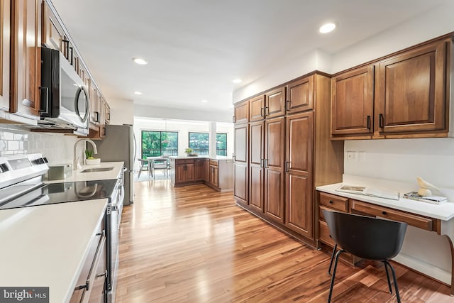 2127 Cabots Point Ln, Reston, VA 20191 - kitchen featuring stainless steel appliances, light wood finished floors, a desk, brown cabinets, and recessed lighting