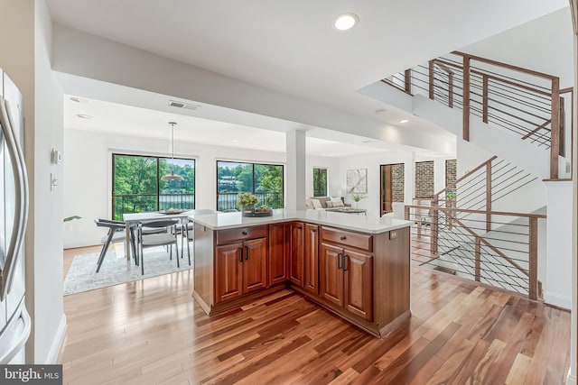 2127 Cabots Point Ln, Reston, VA 20191 - kitchen featuring light wood-style flooring, light countertops, brown cabinetry, open floor plan, and recessed lighting
