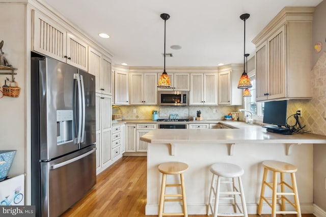 461 Anchor Rd, Tuckerton, NJ 08087 - kitchen featuring stainless steel appliances, a peninsula, light countertops, light wood-type flooring, and backsplash