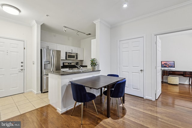 12925 Centre Park Cir Unit 106, Herndon, VA 20171 - kitchen with appliances with stainless steel finishes, rail lighting, a peninsula, light wood-style flooring, and crown molding