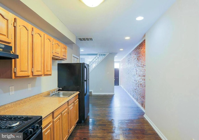 1114 W Cross St, Baltimore, MD 21230 - kitchen featuring brick wall, dark wood-type flooring, light countertops, black appliances, and under cabinet range hood