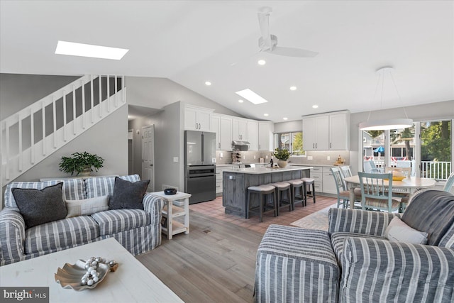 917 Lake View Dr, Bethany Beach, DE 19930 - living area featuring a skylight, ceiling fan, light wood-type flooring, vaulted ceiling, and stairway