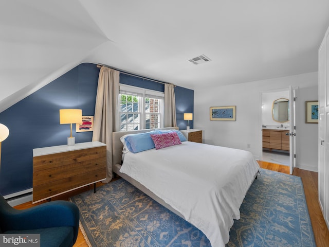 9103 Chickawane Ct, Alexandria, VA 22309 - bedroom with wood finished floors, vaulted ceiling, a baseboard radiator, ensuite bathroom, and a sink