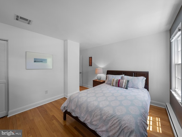 9103 Chickawane Ct, Alexandria, VA 22309 - bedroom with a baseboard heating unit, light wood-style floors, and baseboards