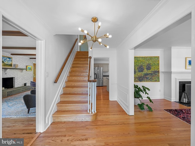9103 Chickawane Ct, Alexandria, VA 22309 - staircase with a brick fireplace, a chandelier, wood finished floors, ornamental molding, and baseboards